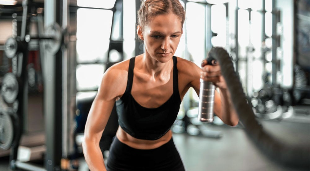 Lybe Clinic: mulher que é atleta de alta performance praticando cordas em academia 