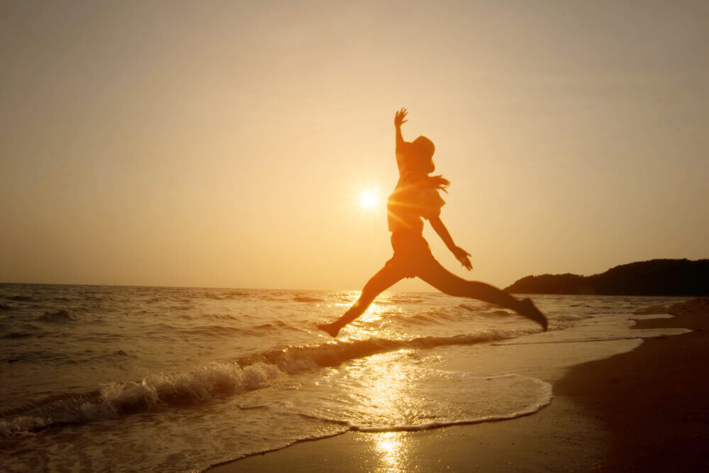 silhouette-woman-jumping-sea-sunset